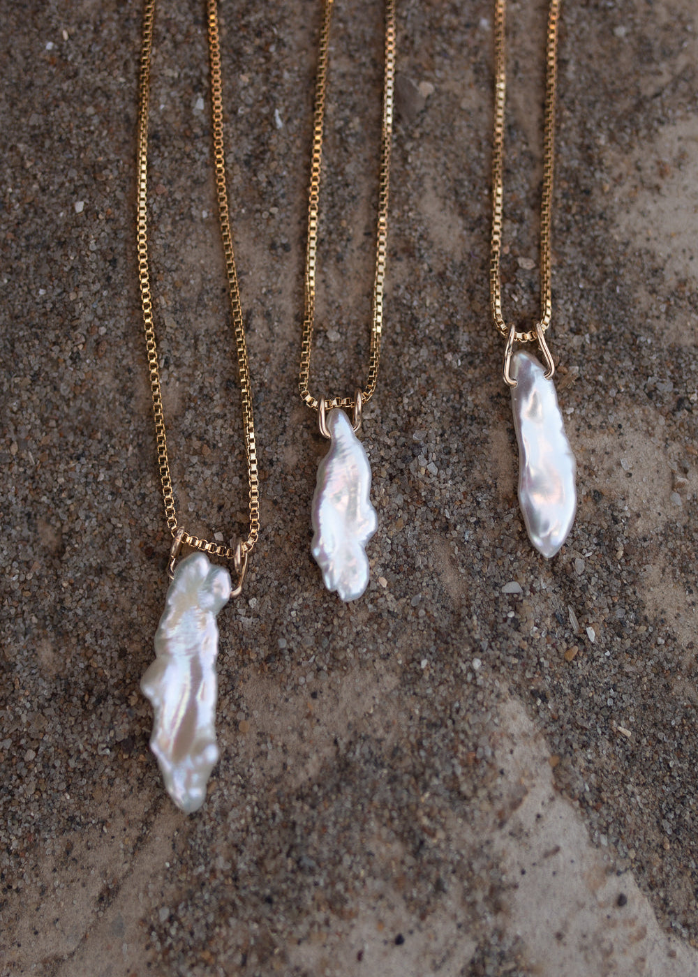 Three Elara necklaces side by side to show the variation in natural pearl pendants used.
