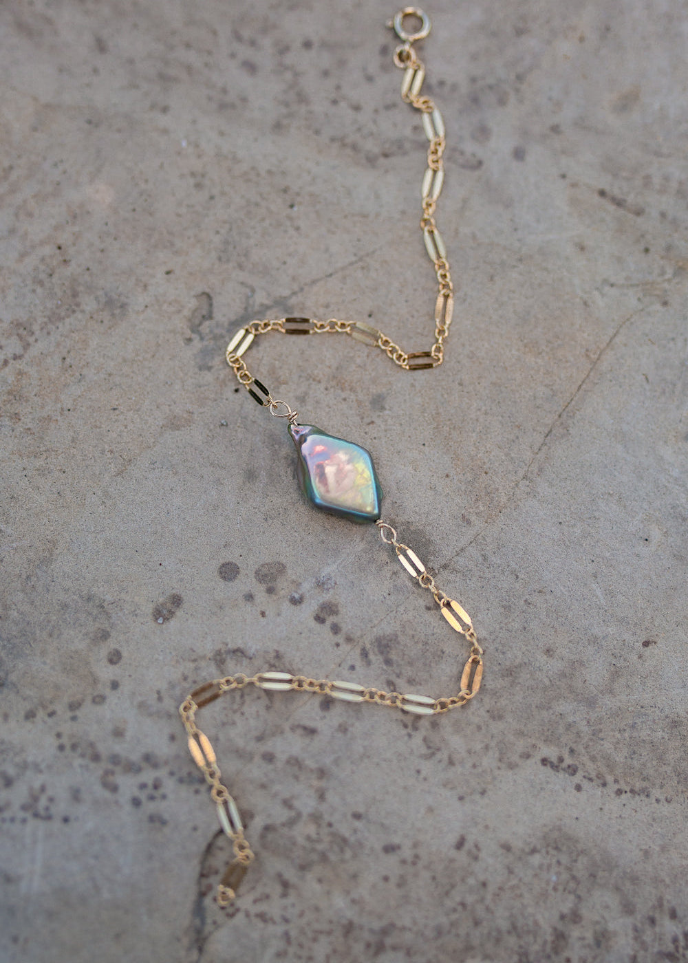 Bracelet with dapped sparkly gold chain and a stunning rainbow green/purple diamond shaped pearl in the center.