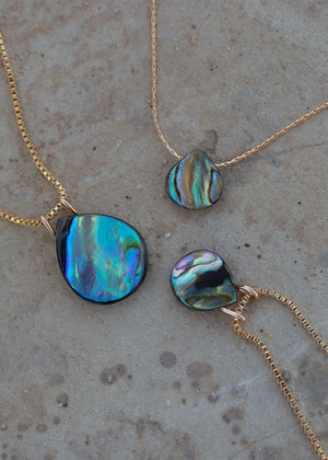 Detailed view of the abalone pendants of varying sizes with and without a gold bail.