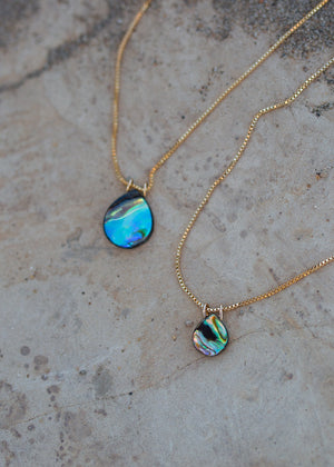Close up view of venetian gold chain with abalone pendants in large and small sizes. Abalone pendants are iridescent blue and green rainbow swirls.