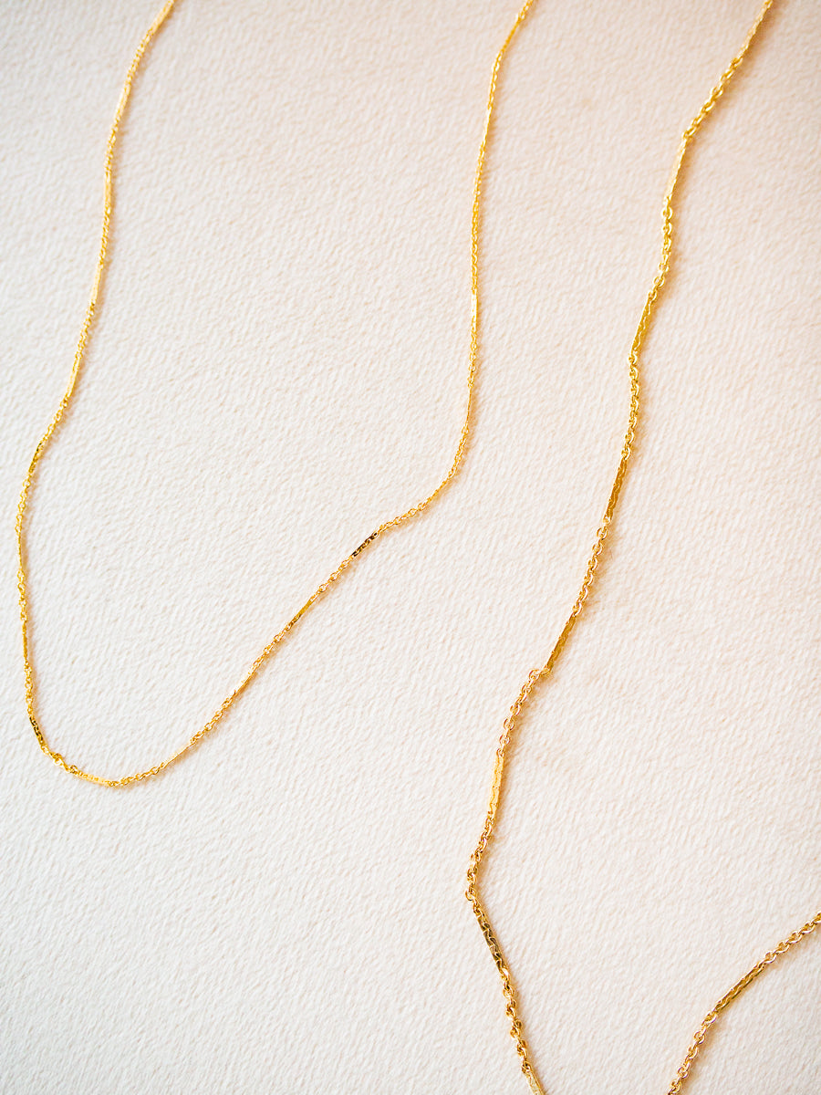 Gold chain necklace on a light beige background