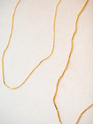 Gold chain necklace on a light beige background