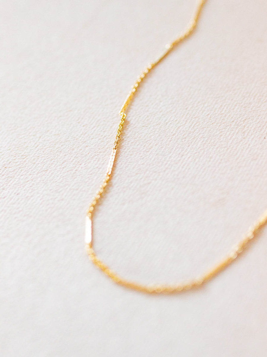 Gold chain necklace on a light beige background