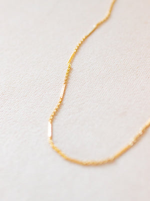 Gold necklace on a light beige background