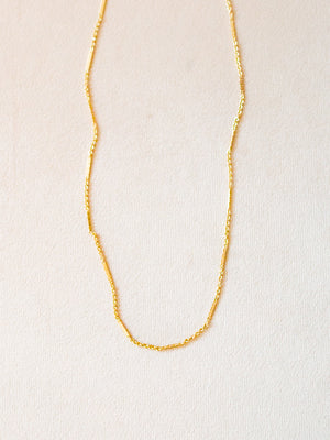Gold chain necklace on a beige background