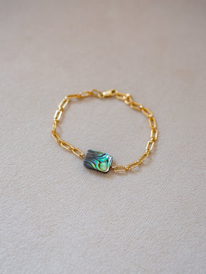 Gold chain bracelet with a green/blue  abalone piece in the center