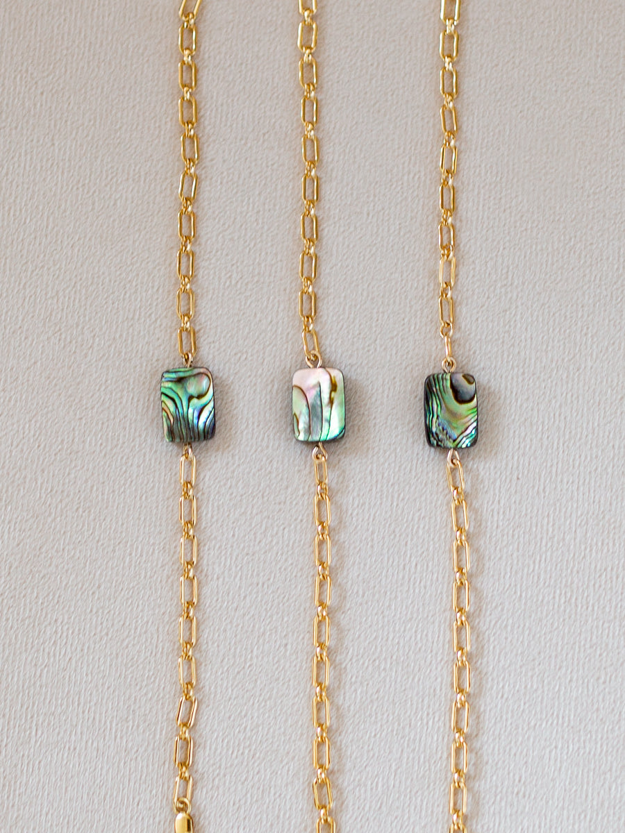 Three gold bracelets with abalone shell beads
