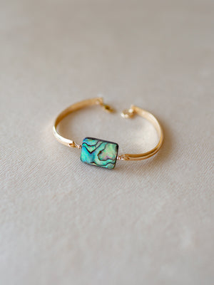 Gold bangle with a colorful abalone centerpiece