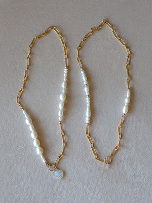 Two pearl necklaces with thick gold chains on a soft beige background