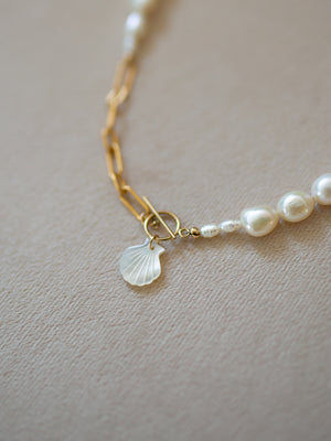 Pearl necklace with a shell charm on a neutral background