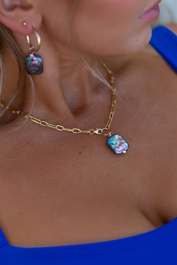 Gold chain necklace with a rectangular peacock blue rainbow pearl pendant.