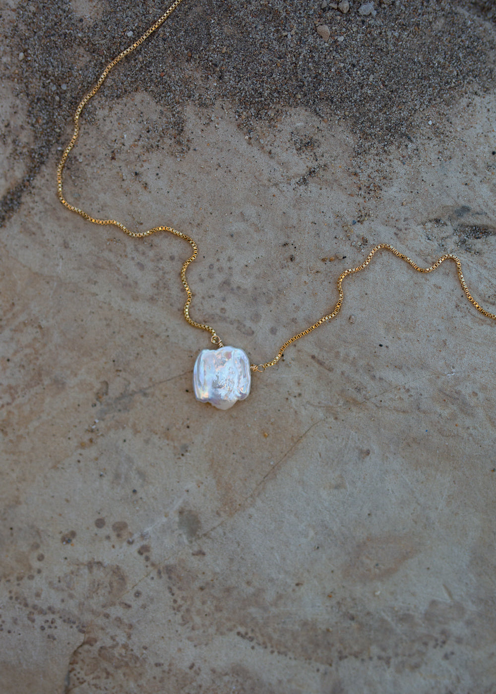 Detailed view of the pearl pendant, shows a beautiful white rainbow luster.