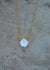 Dainty gold box chain with a large white keishi pearl pendant and a sandstone background