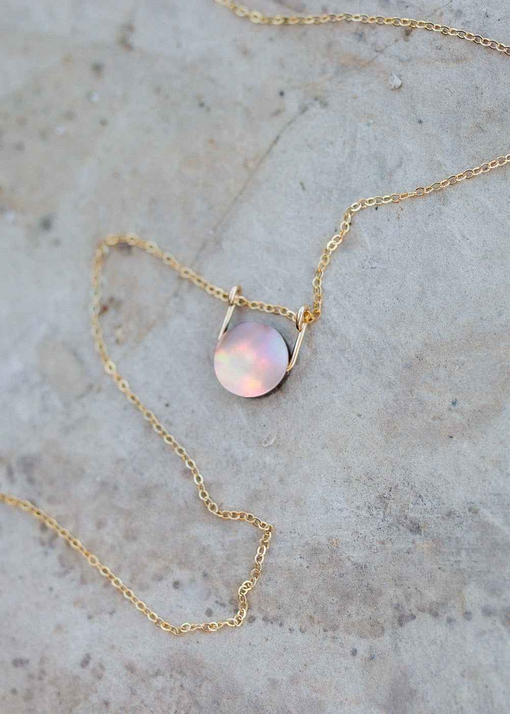 Circular mother of pearl coin with a gold sliding bail and dainty gold cable chain