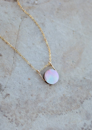 The flip side of the mother of pearl coin pendant, with a lighter auric iridescent color