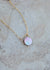 The flip side of the mother of pearl coin pendant, with a lighter auric iridescent color