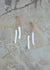 Gold post earrings with long white stick pearls hanging from chains
