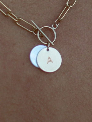 Detailed view of necklace charms with initial stamp